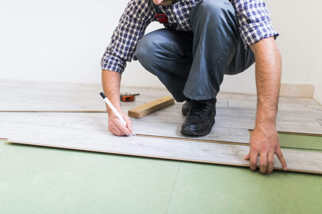 young worker lining a floor with laminated flooring boards